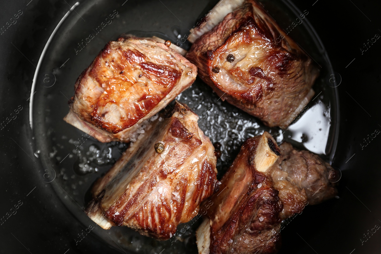 Photo of Top view of delicious pork ribs in modern multi cooker, closeup