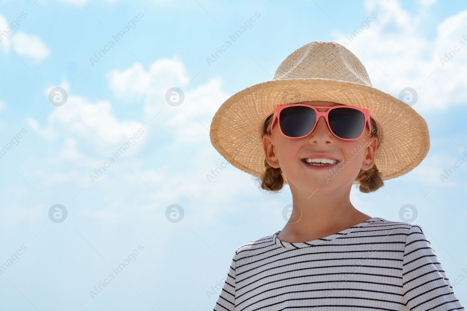 Photo of Little girl wearing sunglasses and hat at beach on sunny day. Space for text