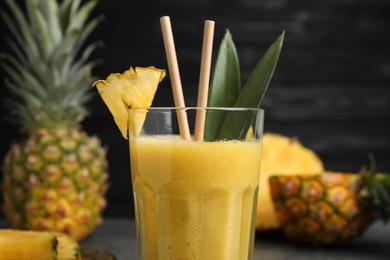 Photo of Tasty pineapple smoothie and fruit on blurred background, closeup