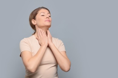 Photo of Woman suffering from sore throat on light grey background. Space for text