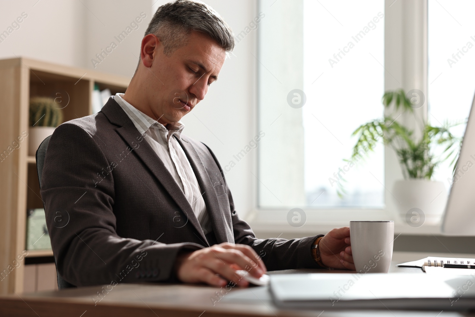 Photo of Man with cup of drink snoozing at table in office