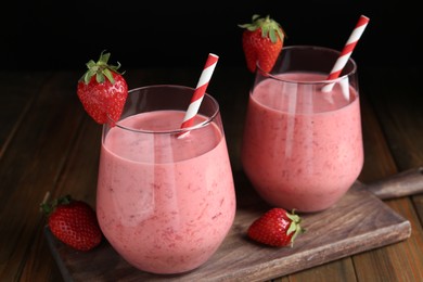 Photo of Tasty strawberry smoothies in glasses on wooden board