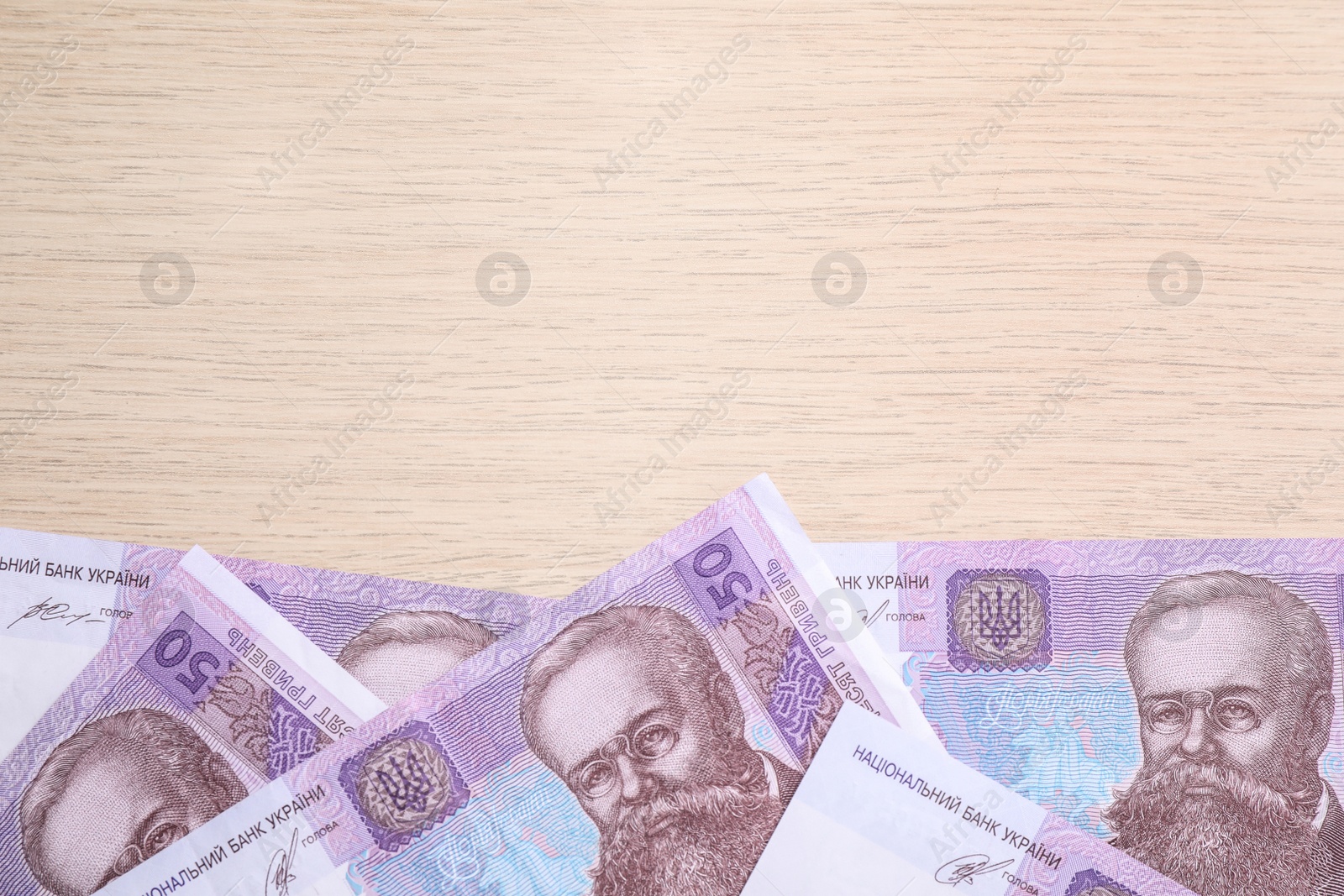 Photo of Ukrainian money on wooden background, flat lay. Space for text