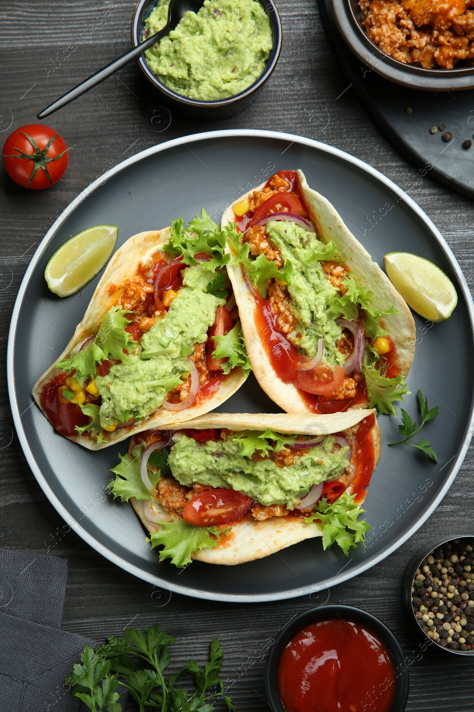 Photo of Delicious tacos with guacamole, meat and vegetables on wooden table, flat lay