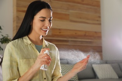 Photo of Woman applying spray sanitizer onto hand at home