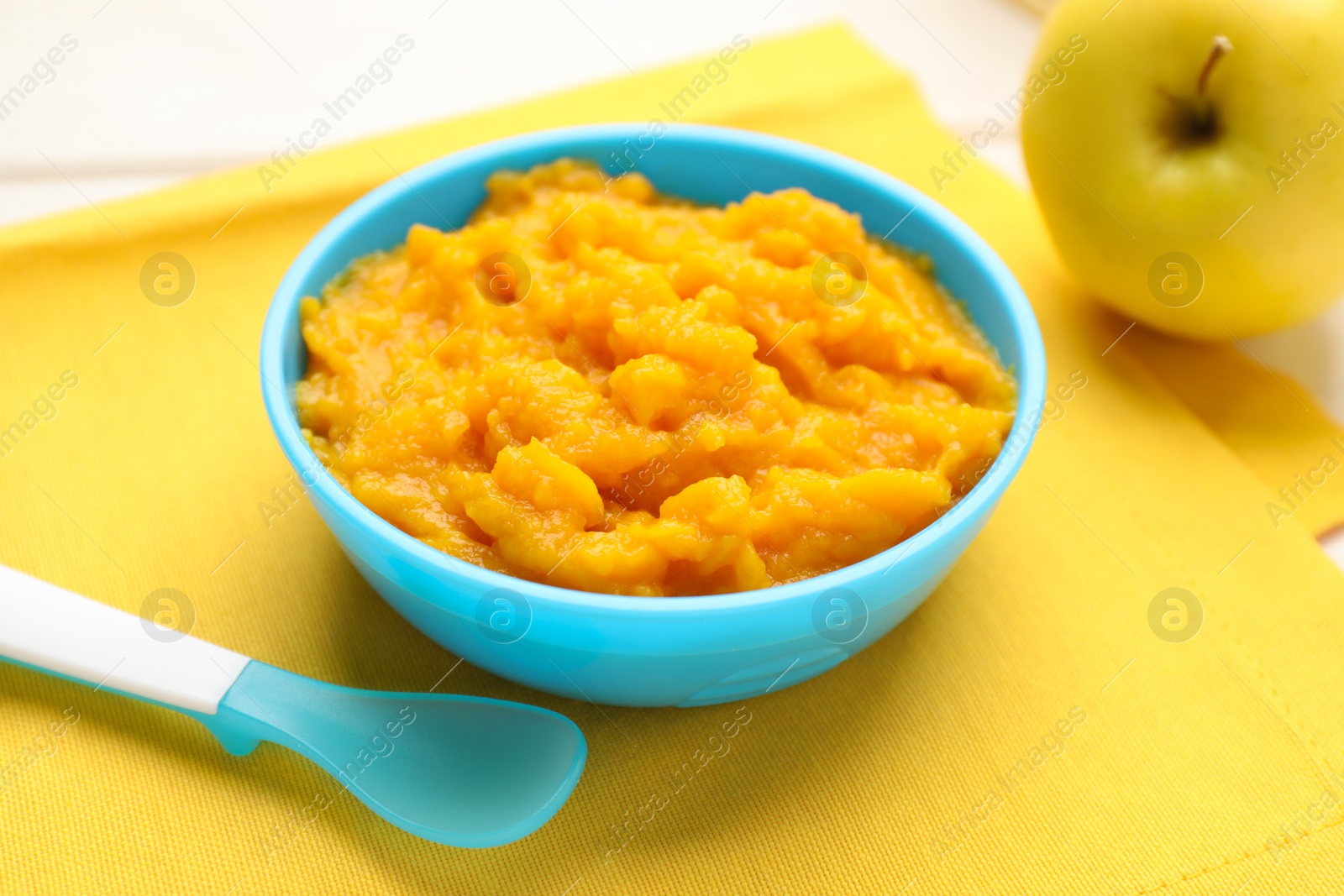 Photo of Plastic dishware with healthy baby food on white table, closeup