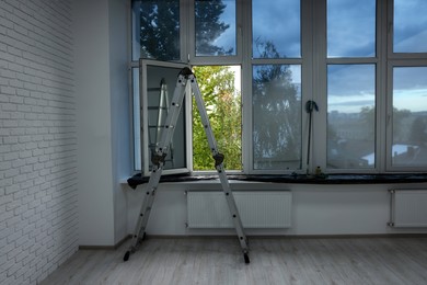 Photo of Ladder in empty renovated room with windows