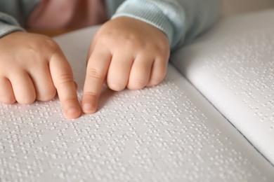 Blind child reading book written in Braille, closeup
