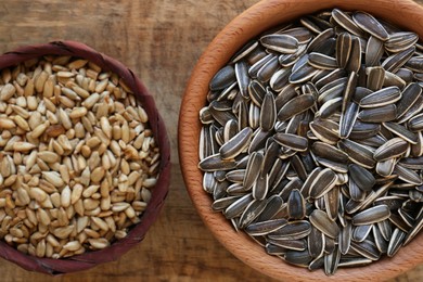 Bowls with organic sunflower seeds on wooden table, flat lay