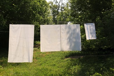 Photo of Washing line with clean laundry and clothespins outdoors