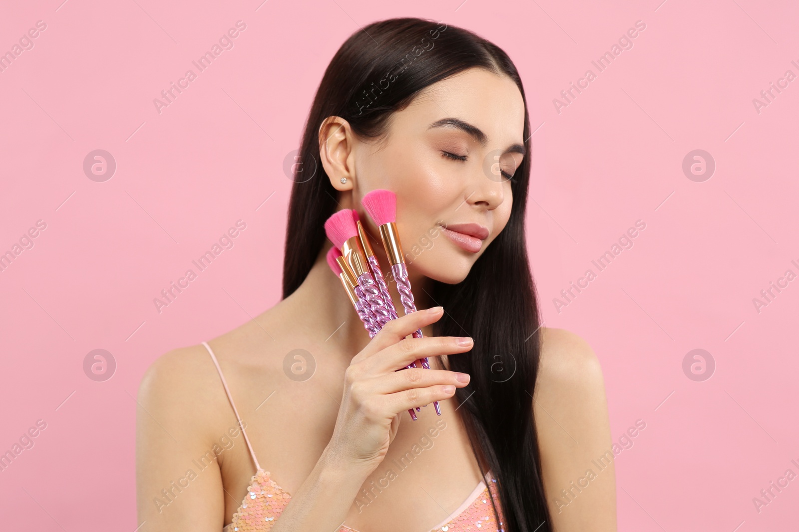 Photo of Beautiful woman with different makeup brushes on pink background