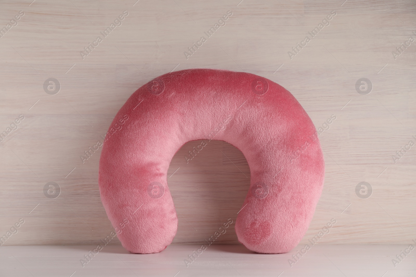 Photo of Pink travel pillow on light wooden background