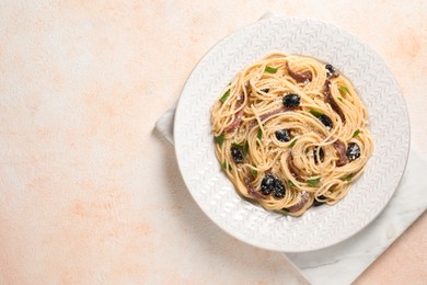 Delicious pasta with anchovies, olives and parmesan cheese on beige textured table, top view. Space for text