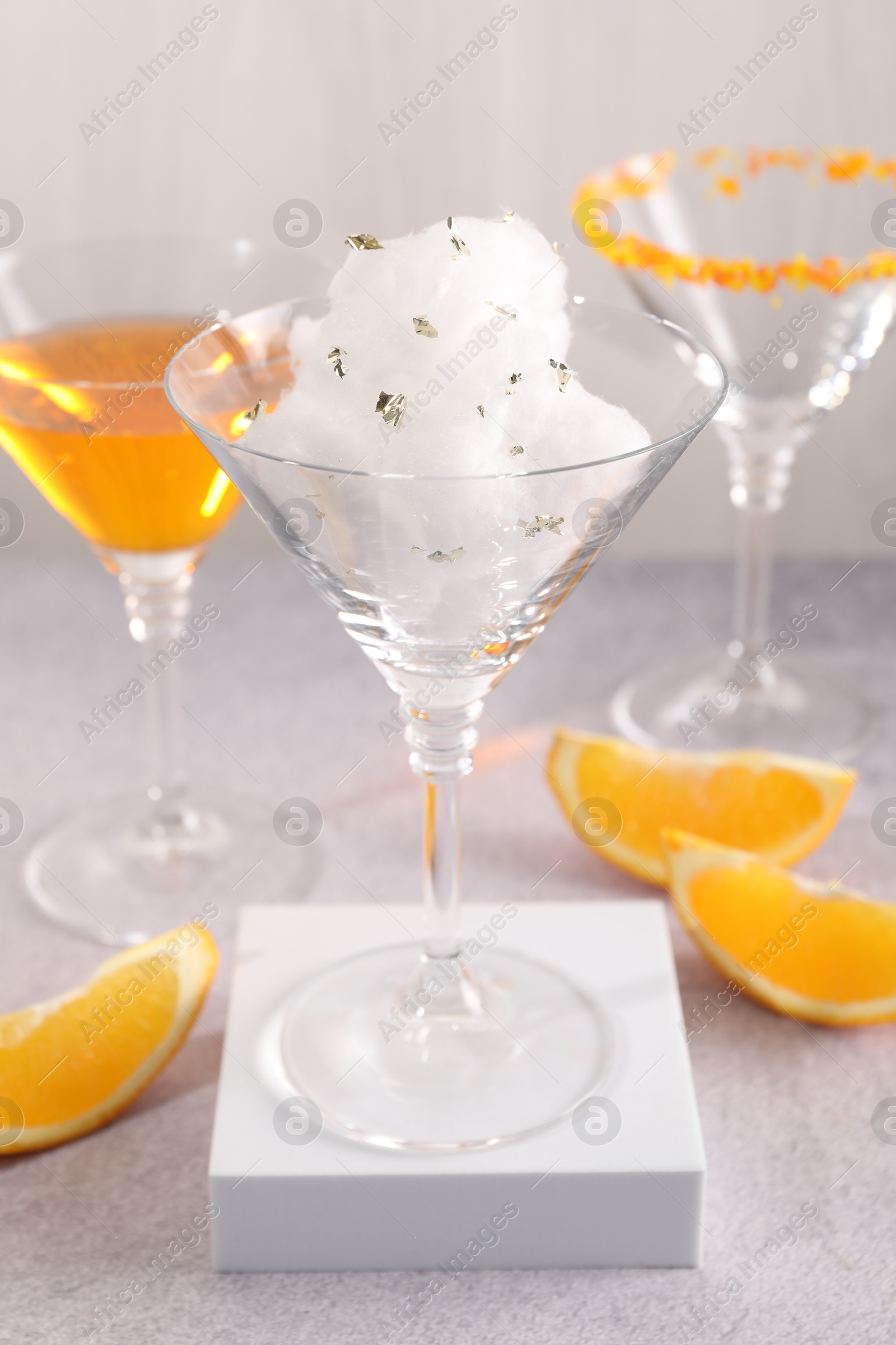 Photo of Tasty cotton candy cocktail in glass and other alcoholic drinks on gray table