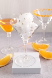 Tasty cotton candy cocktail in glass and other alcoholic drinks on gray table