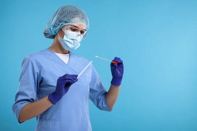 Laboratory testing. Doctor with cotton swab and tube on light blue background, space for text