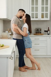 Affectionate young couple kissing in light kitchen