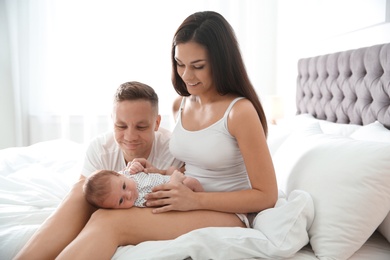 Happy couple with their newborn baby on bed