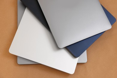 Photo of Different modern laptops on brown background, top view