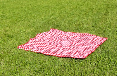 Photo of Checkered picnic tablecloth on fresh green grass outdoors