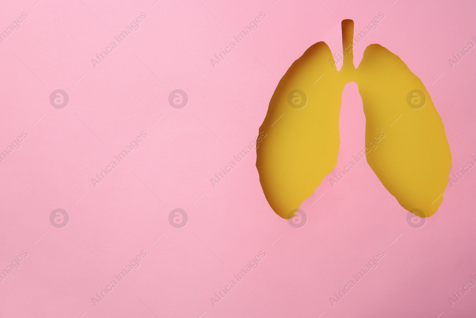 Photo of Pink paper with hole in shape of human lungs, top view. Space for text
