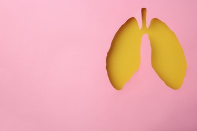 Photo of Pink paper with hole in shape of human lungs, top view. Space for text