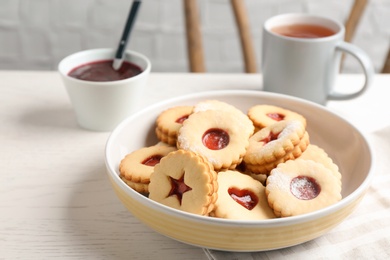 Photo of Traditional Christmas Linzer cookies with sweet jam and cup of tea on table