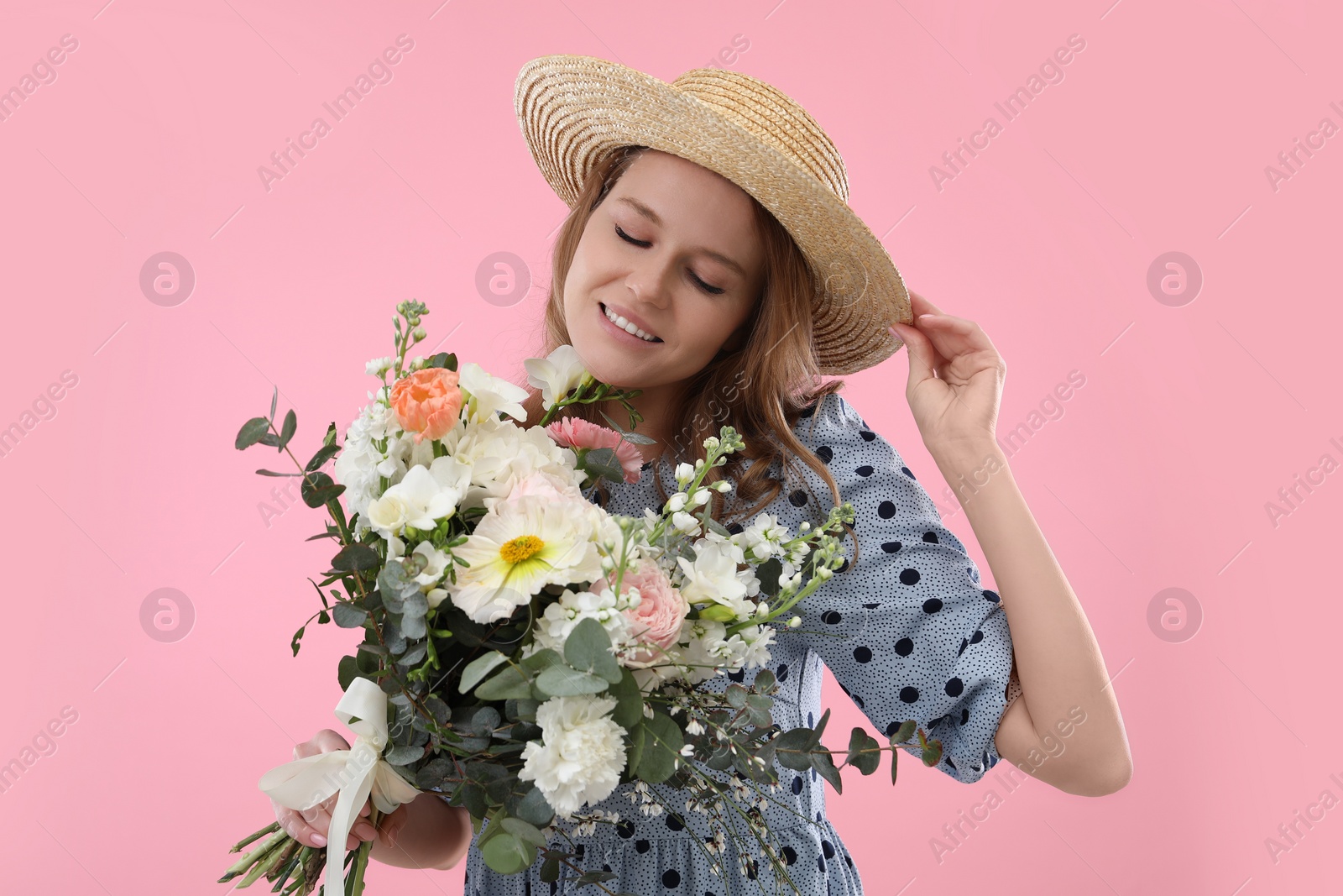 Photo of Beautiful woman in straw hat with bouquet of flowers on pink background