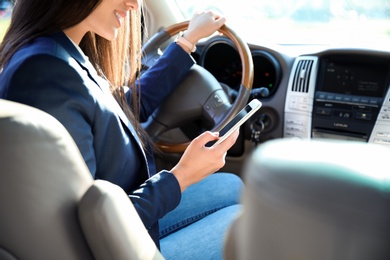 Photo of Young businesswoman with smartphone on driver's seat of car