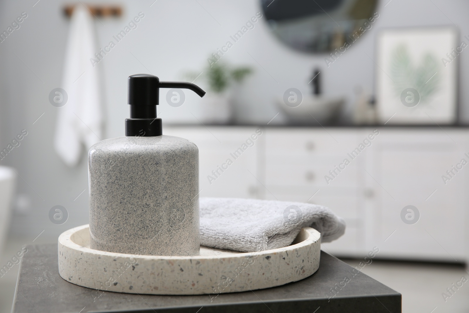 Photo of Dispenser of liquid soap and clean towel on table in bathroom. Space for text