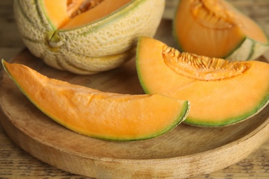 Tasty fresh cut melons on wooden tray, closeup