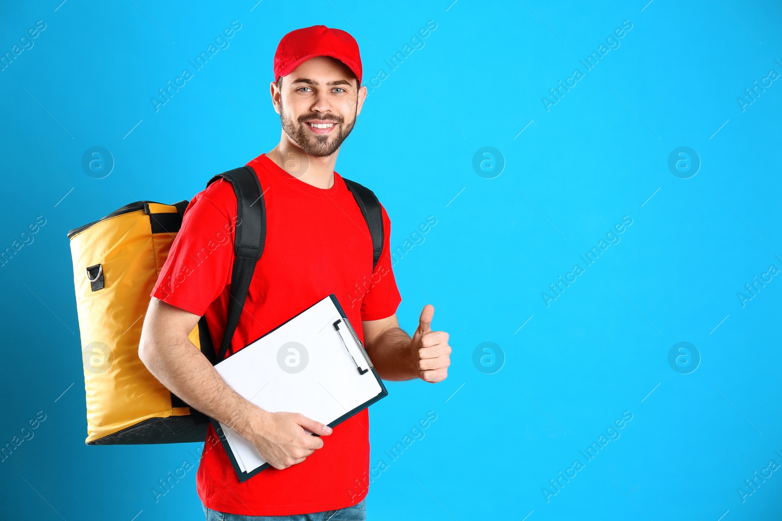 Photo of Courier with thermo bag and clipboard on light blue background, space for text. Food delivery service