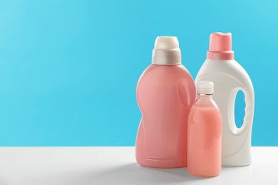 Photo of Bottles of laundry detergents on white table. Space for text