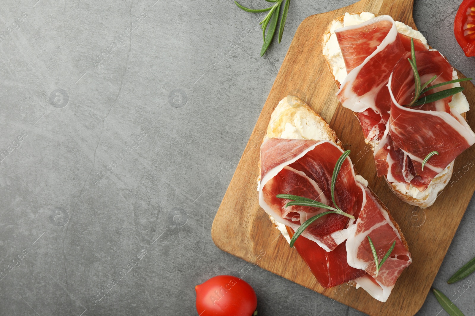 Photo of Tasty sandwiches with cured ham on grey table, flat lay. Space for text