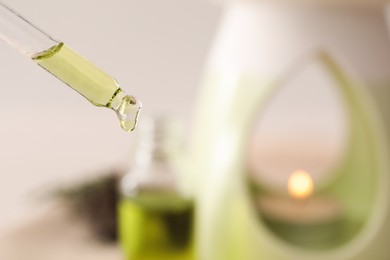 Photo of Pipette with coniferous essential oil for aroma lamp on blurred background, closeup