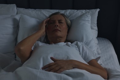 Woman suffering from headache in bed at night