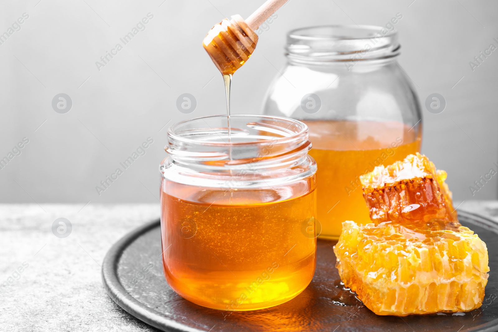Photo of Tasty fresh aromatic honey on grey table