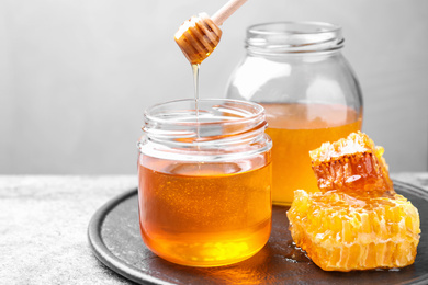 Photo of Tasty fresh aromatic honey on grey table