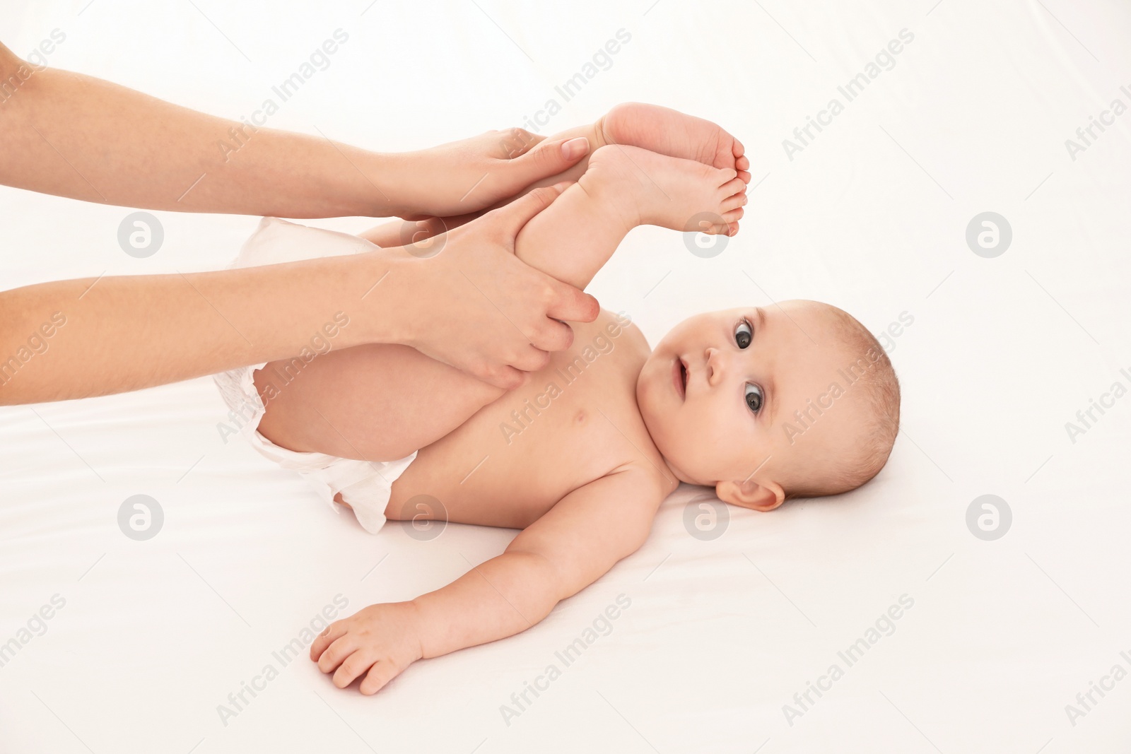 Photo of Mother and her cute child on white bed. Baby massage and exercises