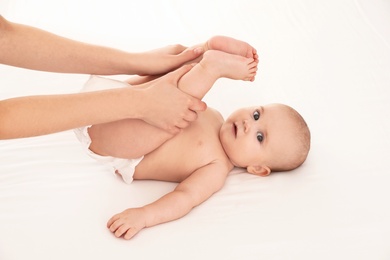 Mother and her cute child on white bed. Baby massage and exercises