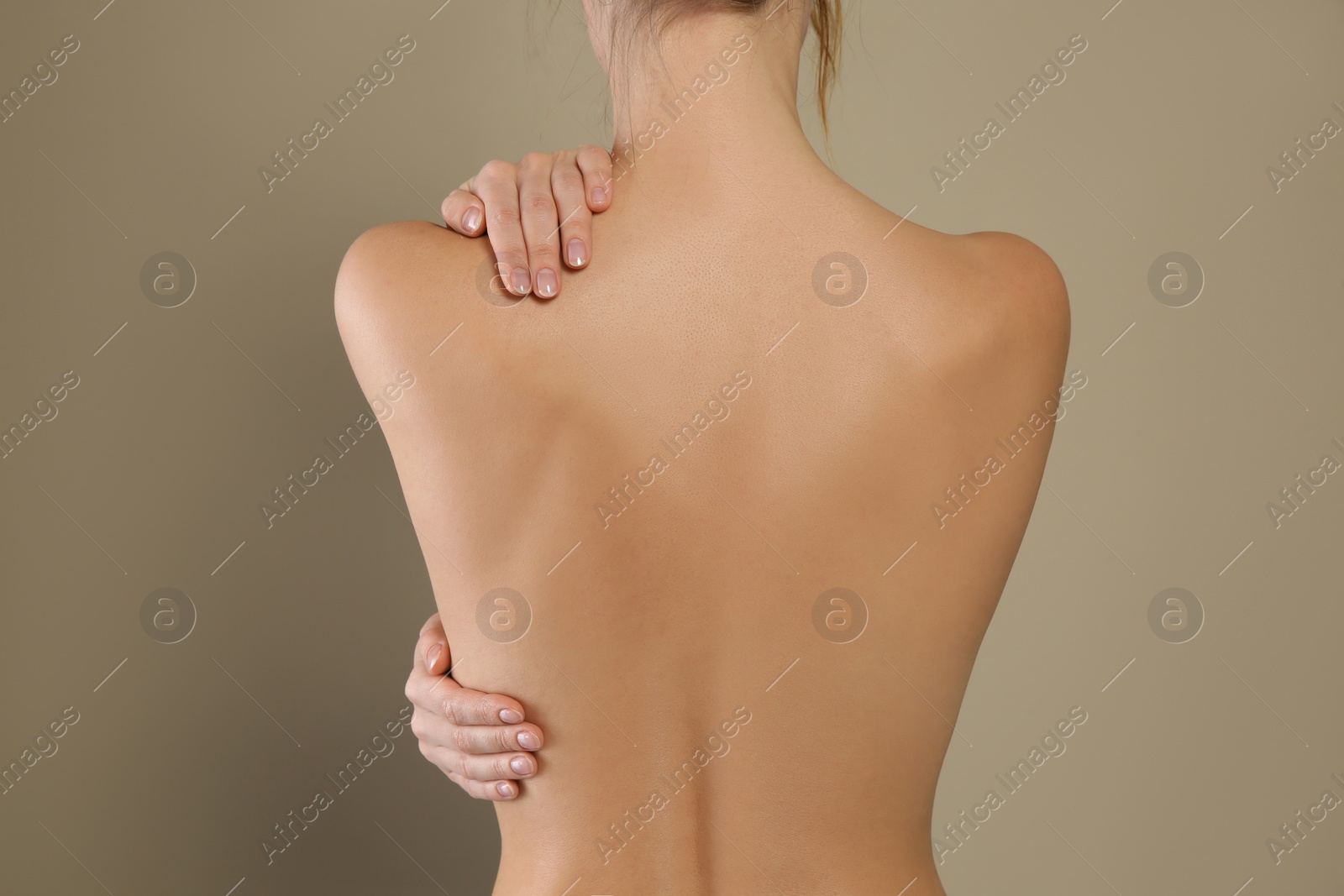 Photo of Back view of woman with perfect smooth skin on beige background, closeup. Beauty and body care