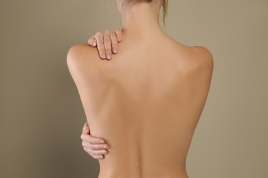Photo of Back view of woman with perfect smooth skin on beige background, closeup. Beauty and body care