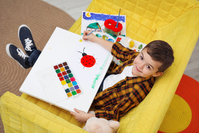 Photo of Little child painting on sofa at home, above view