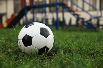 Photo of Wet leather soccer ball on grass outdoors, space for text