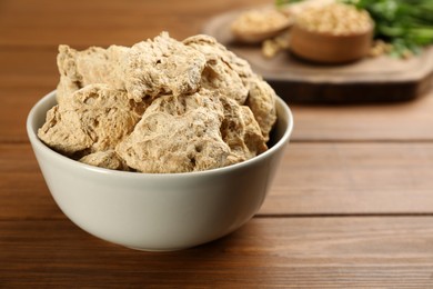 Photo of Dehydrated soy meat chunks in bowl on wooden table, closeup