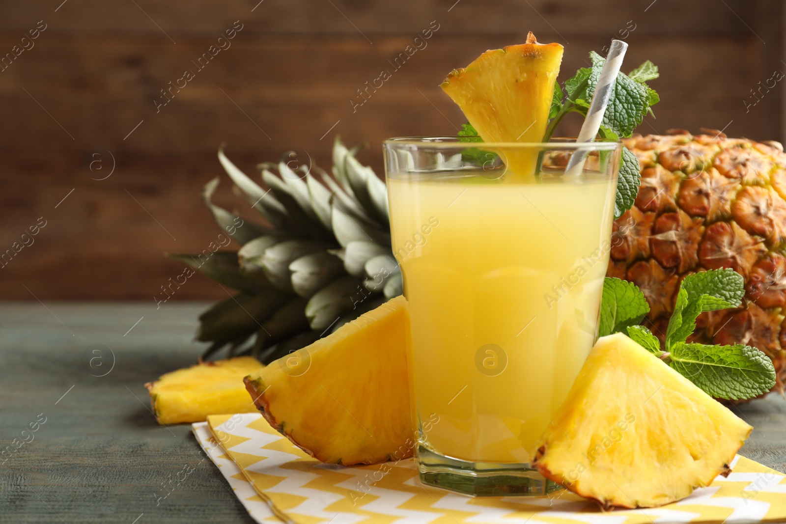 Photo of Delicious pineapple juice and fresh fruit on blue wooden table, closeup