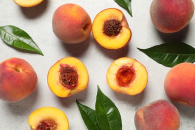 Delicious ripe peaches and leaves on light grey textured table, flat lay