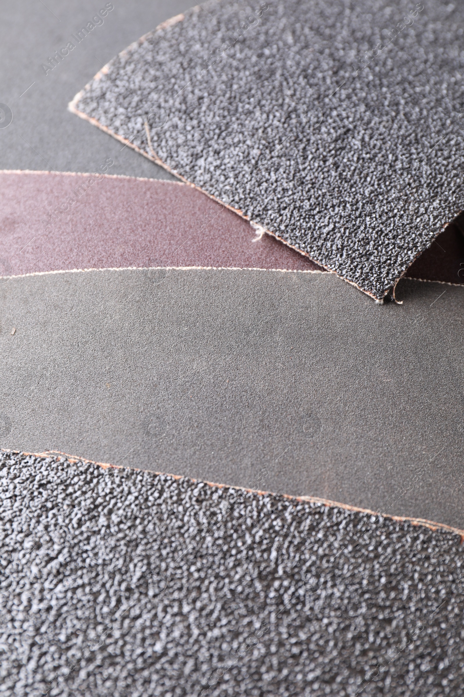 Photo of Many sheets of sandpaper as background, closeup