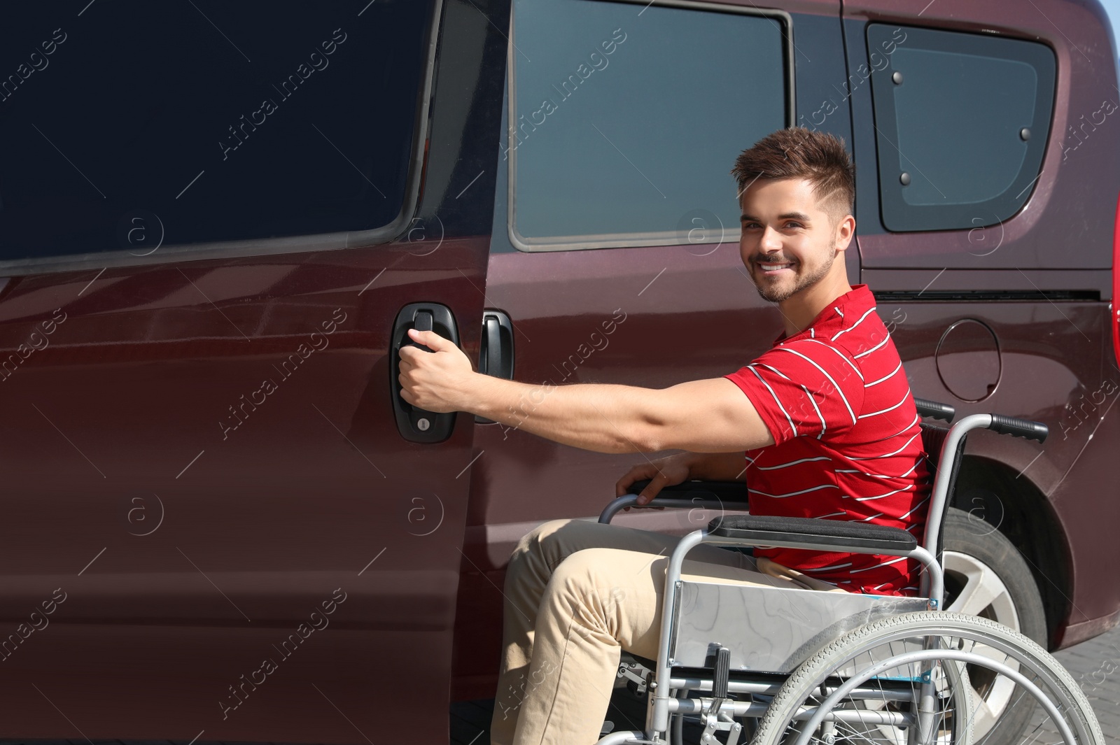 Photo of Young man in wheelchair opening door of his van outdoors