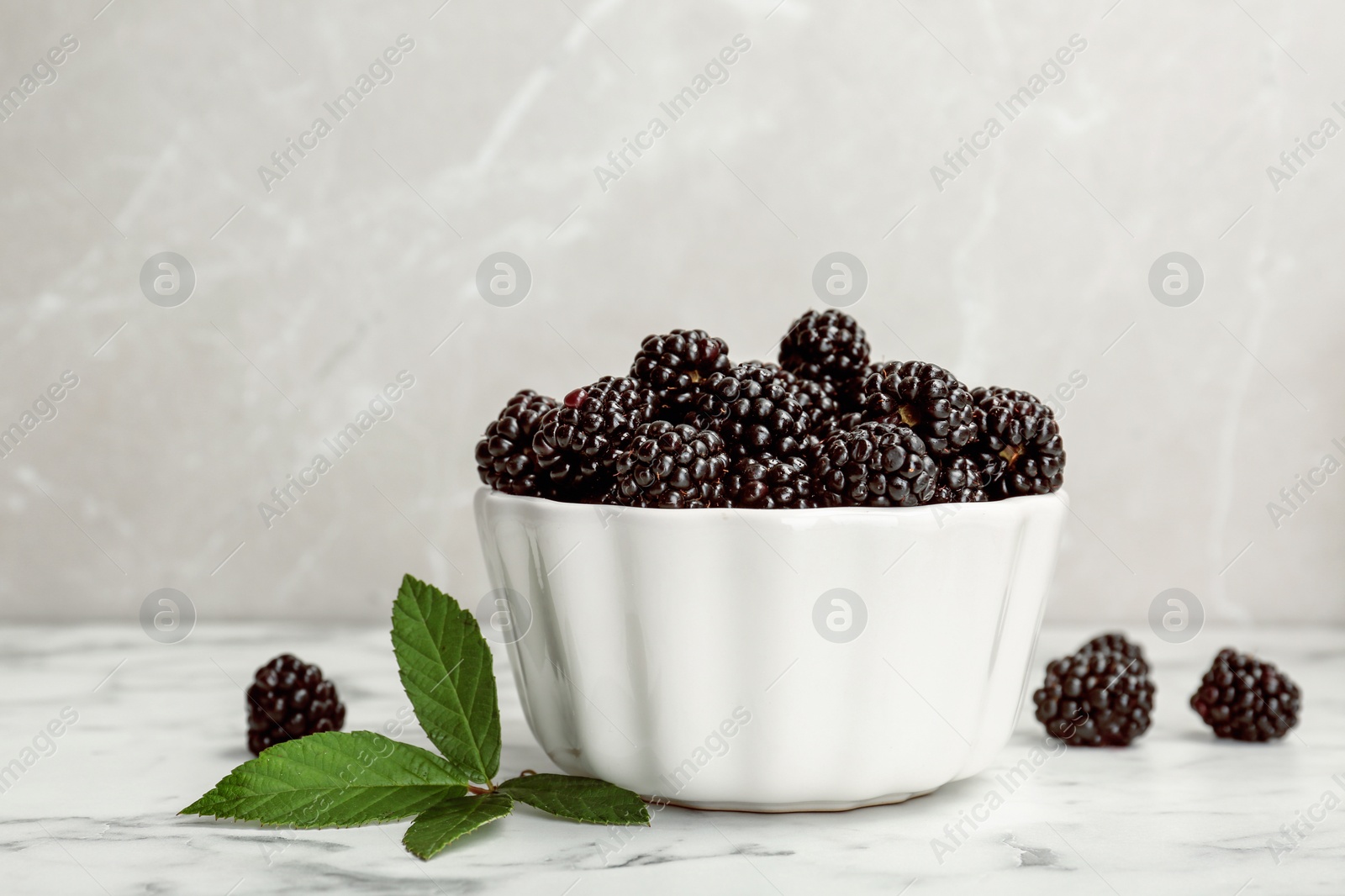 Photo of Bowl of fresh blackberry on marble table